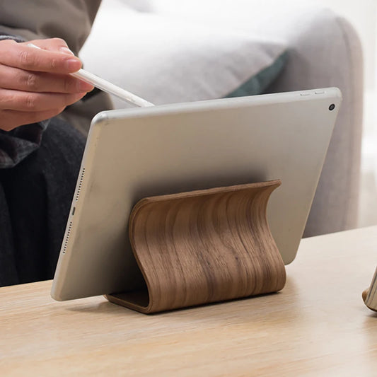 Wooden tablet stand holding a tablet on a table with a person using a stylus.