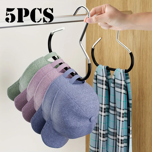 Metal hanger with five colorful caps and a scarf on a wooden door.