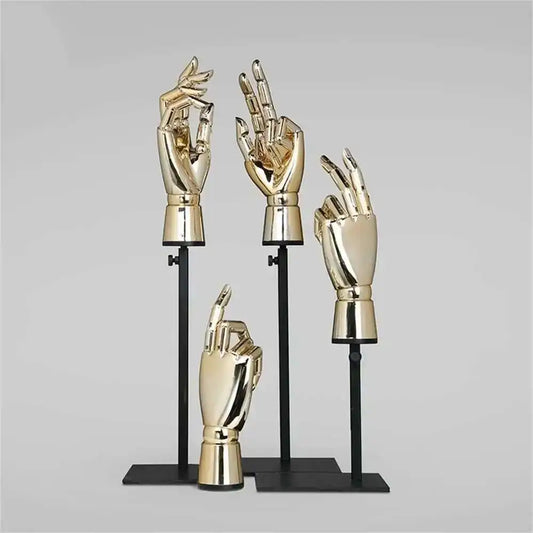 Set of gold hand sculptures on black stands against a gray background